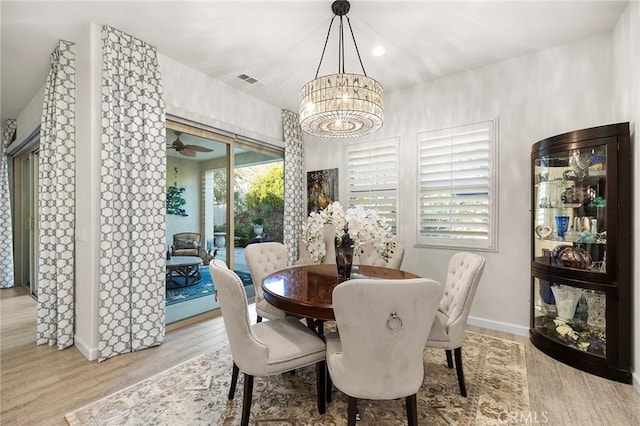 dining area featuring ceiling fan with notable chandelier and light hardwood / wood-style flooring