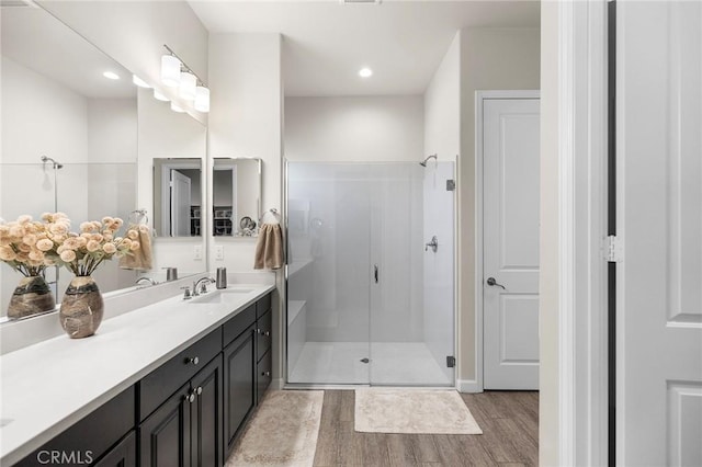 bathroom with a shower with shower door, hardwood / wood-style floors, and vanity