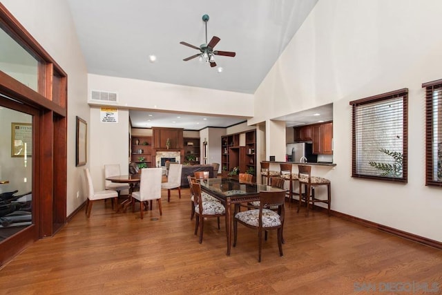 dining room featuring ceiling fan, a high ceiling, and wood-type flooring