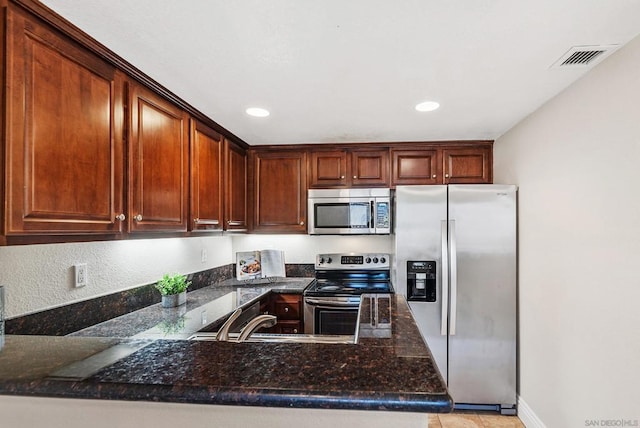 kitchen featuring dark stone countertops, kitchen peninsula, sink, appliances with stainless steel finishes, and light tile patterned floors