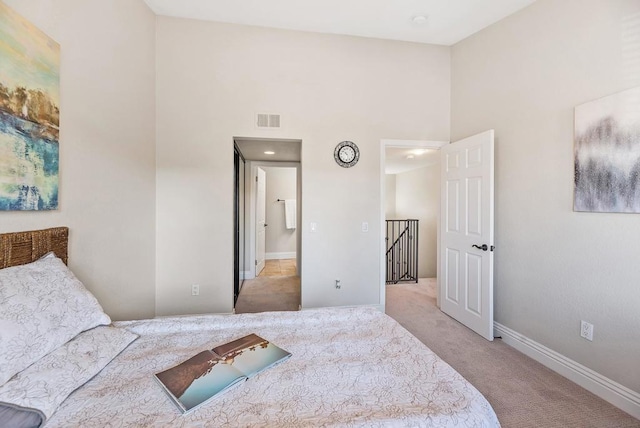 carpeted bedroom featuring a high ceiling and ensuite bath