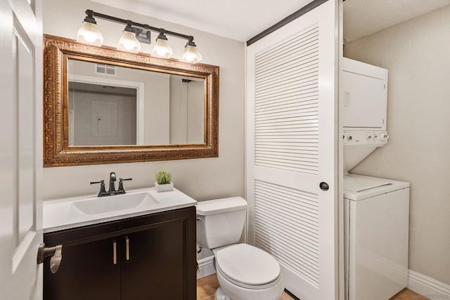 bathroom featuring stacked washer / dryer, toilet, and vanity