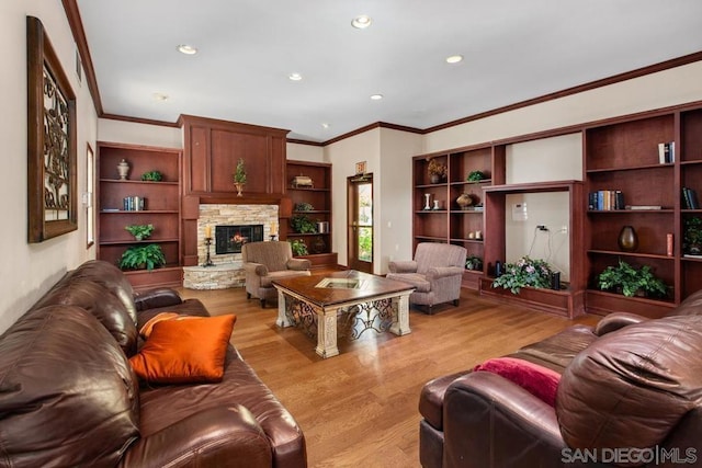 living room with light wood-type flooring, a stone fireplace, and ornamental molding