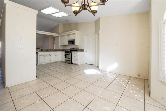 kitchen featuring stainless steel appliances, vaulted ceiling, a chandelier, pendant lighting, and white cabinets