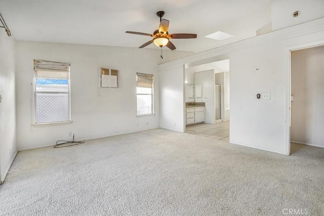 interior space with ceiling fan, light colored carpet, a wall mounted AC, and plenty of natural light