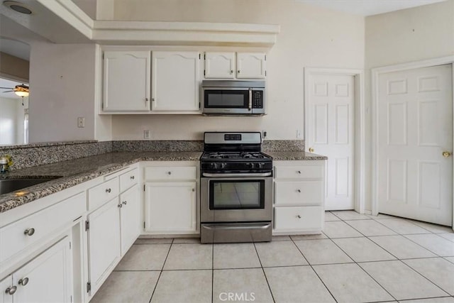 kitchen featuring light tile patterned floors, stainless steel appliances, white cabinets, and ceiling fan