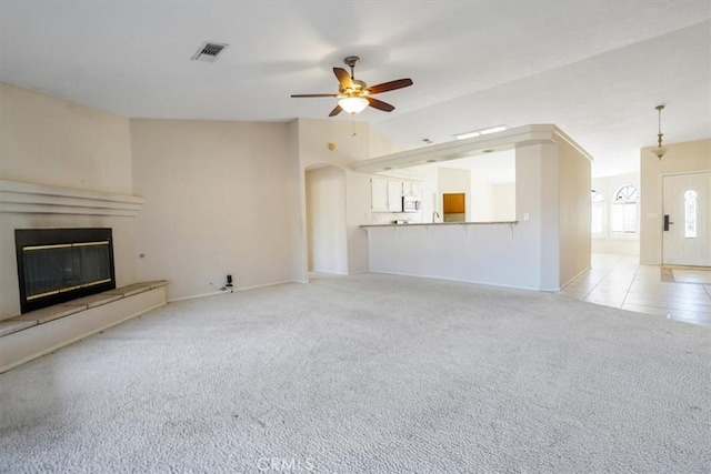 unfurnished living room featuring ceiling fan and light carpet