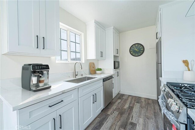 kitchen featuring light stone countertops, dark wood-type flooring, white cabinetry, stainless steel appliances, and sink