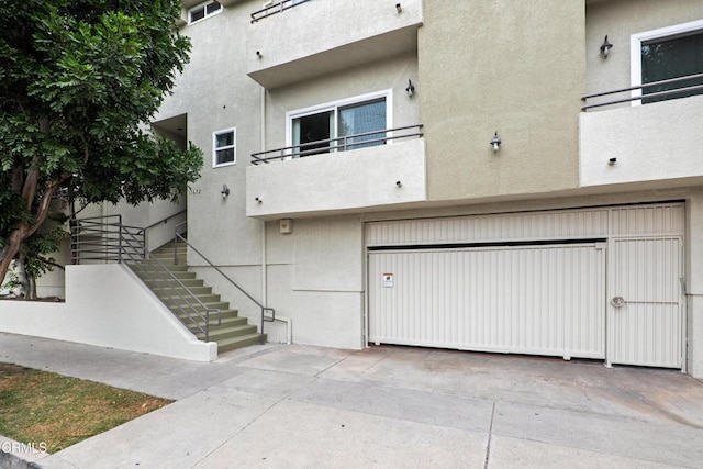 view of building exterior featuring an attached garage and stairs