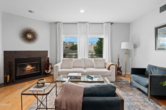 living room featuring recessed lighting, visible vents, a fireplace with flush hearth, wood finished floors, and baseboards