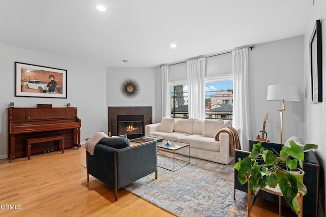 living area with light wood-type flooring, recessed lighting, and a glass covered fireplace