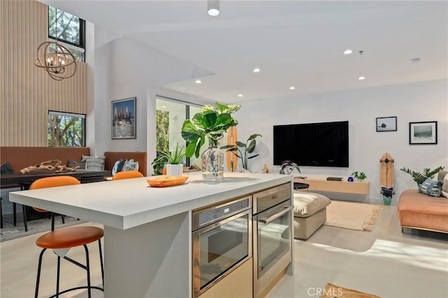 kitchen featuring a wealth of natural light, stainless steel oven, a breakfast bar, and a notable chandelier