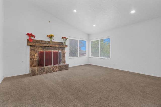 unfurnished living room featuring vaulted ceiling, carpet, and a stone fireplace