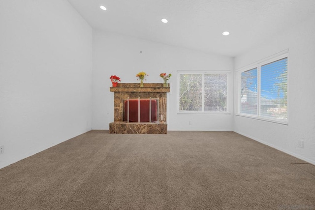 unfurnished living room featuring carpet flooring, lofted ceiling, and a stone fireplace