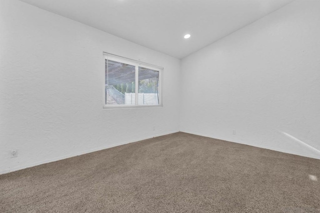 carpeted spare room with vaulted ceiling