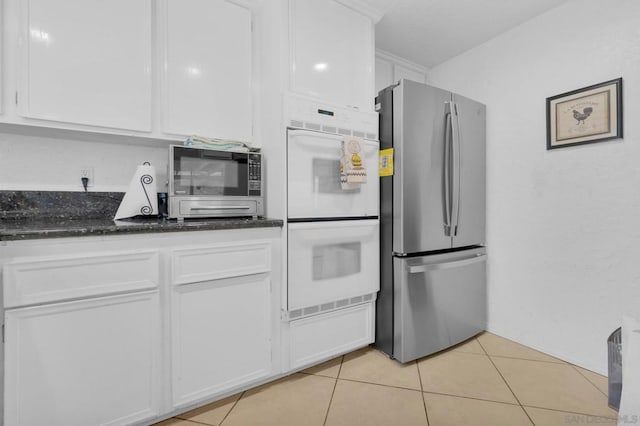 kitchen featuring light tile patterned floors, white cabinetry, appliances with stainless steel finishes, and dark stone countertops