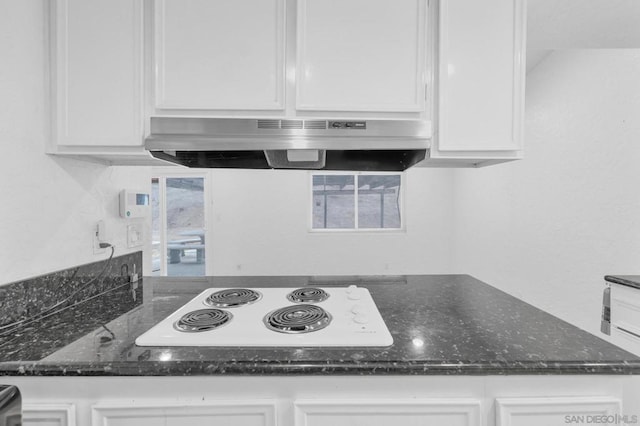 kitchen featuring white cabinets, dark stone countertops, and white electric cooktop