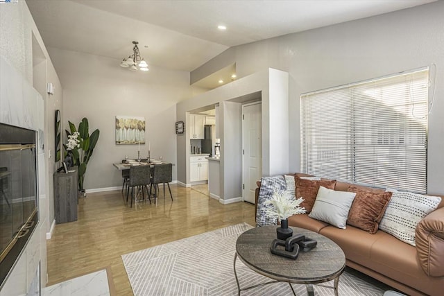 living room featuring light wood-type flooring, vaulted ceiling, and a chandelier