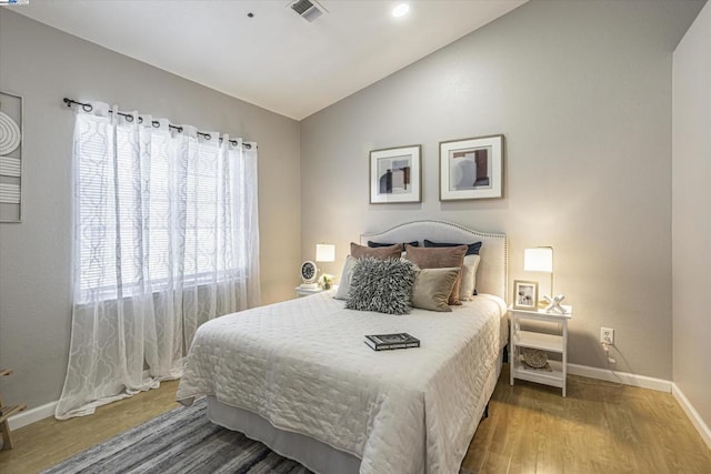 bedroom featuring vaulted ceiling, hardwood / wood-style flooring, and multiple windows