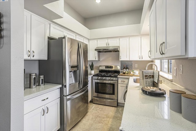 kitchen with light stone counters, white cabinets, appliances with stainless steel finishes, and sink