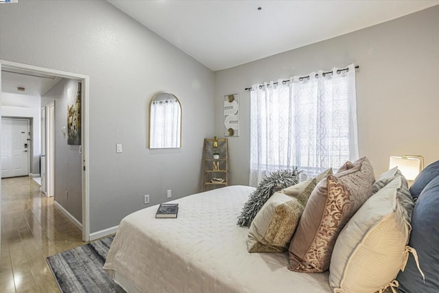 bedroom featuring multiple windows, hardwood / wood-style floors, and vaulted ceiling