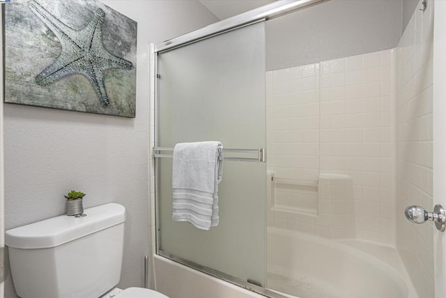 bathroom with toilet and bath / shower combo with glass door