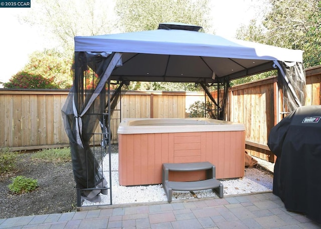 view of patio with a gazebo, a hot tub, and area for grilling