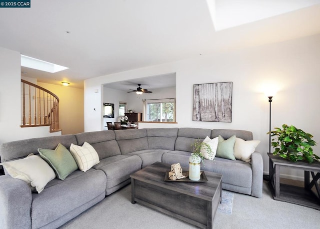 carpeted living room with ceiling fan and a skylight