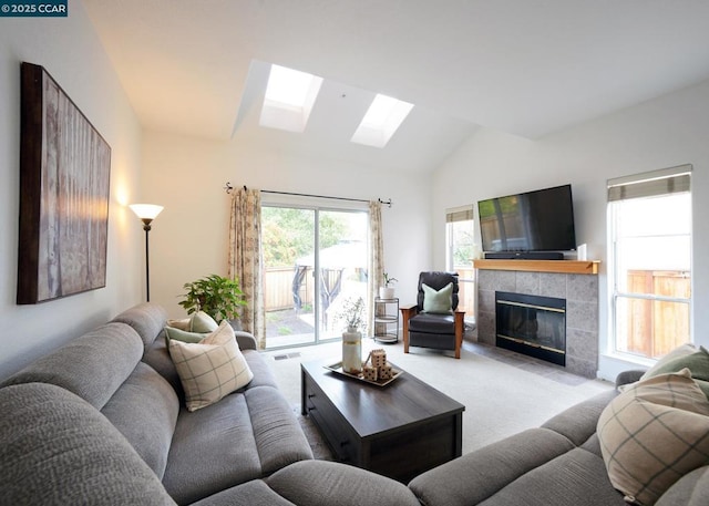 carpeted living room with a tile fireplace and vaulted ceiling