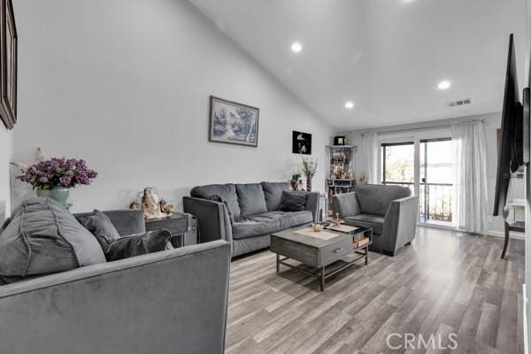 living room featuring light wood-type flooring and high vaulted ceiling