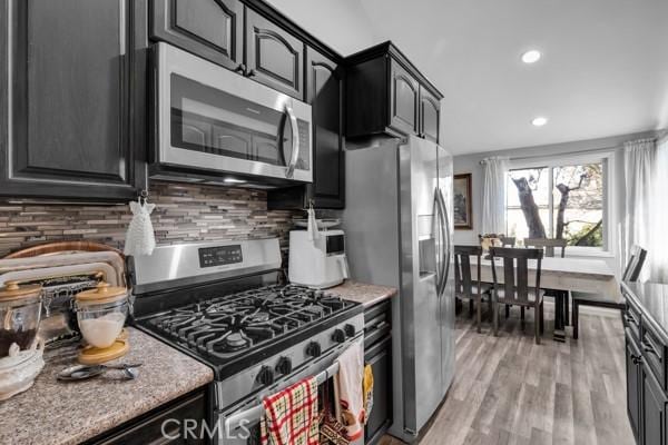 kitchen with light wood-type flooring, stainless steel appliances, and backsplash