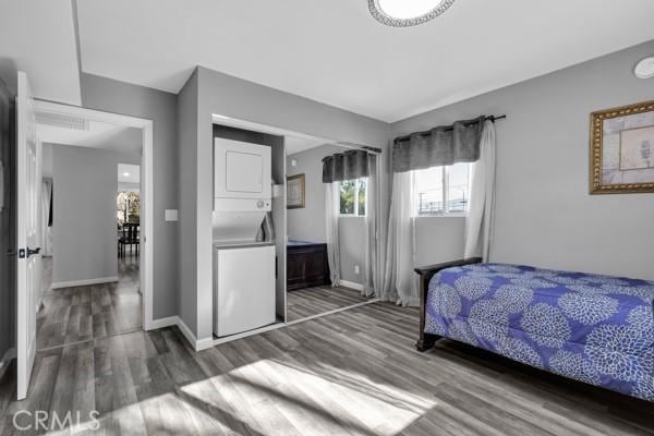 bedroom with stacked washer / drying machine and dark hardwood / wood-style floors