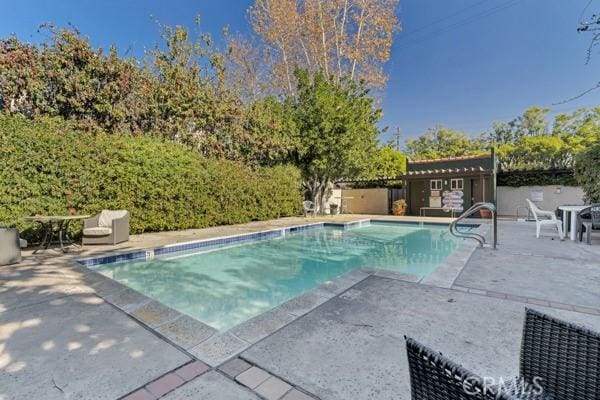 view of pool featuring a shed and a patio