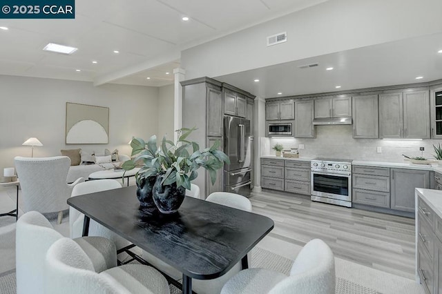 kitchen with tasteful backsplash, light hardwood / wood-style floors, beam ceiling, gray cabinetry, and high quality appliances