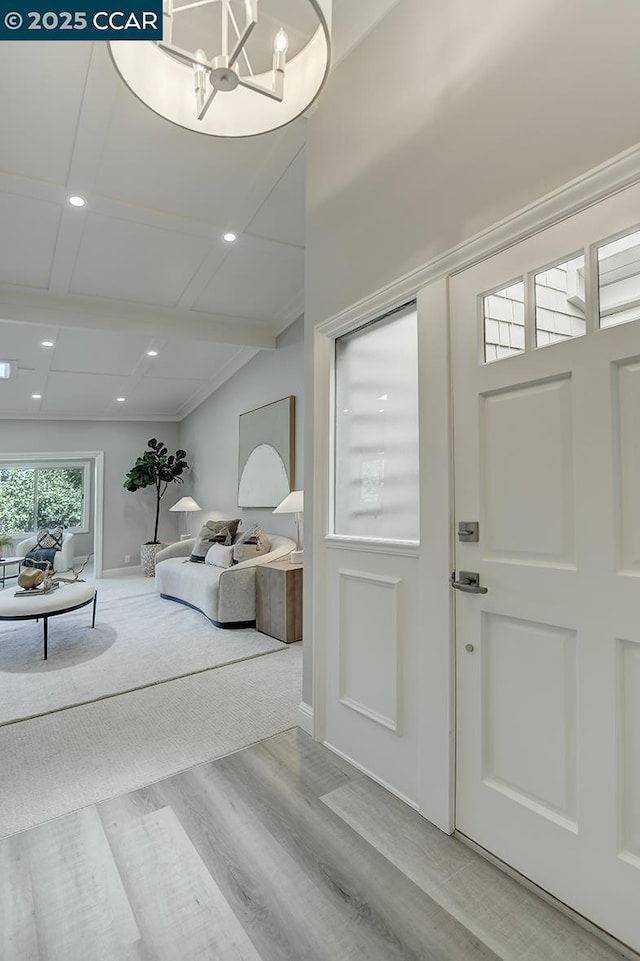 entrance foyer with light hardwood / wood-style flooring, beam ceiling, and an inviting chandelier