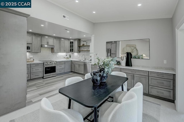 kitchen with backsplash, gray cabinetry, and stainless steel appliances