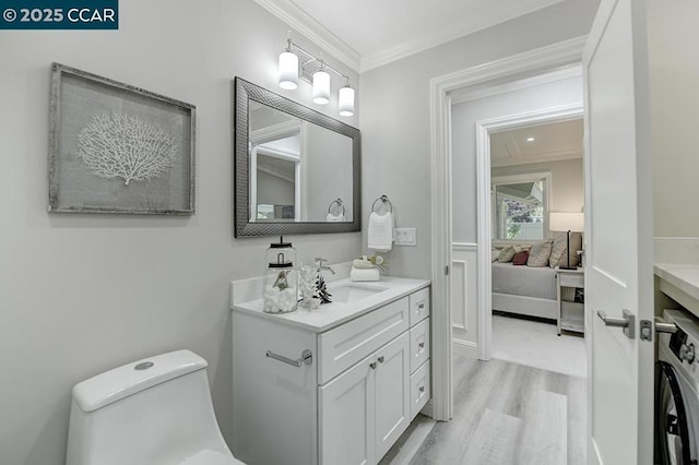 bathroom featuring toilet, hardwood / wood-style flooring, washer / clothes dryer, crown molding, and vanity