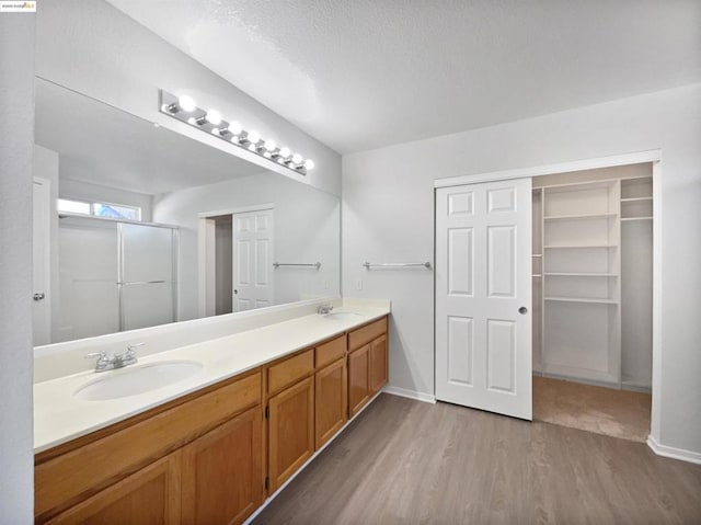 bathroom with an enclosed shower, vanity, wood-type flooring, and a textured ceiling