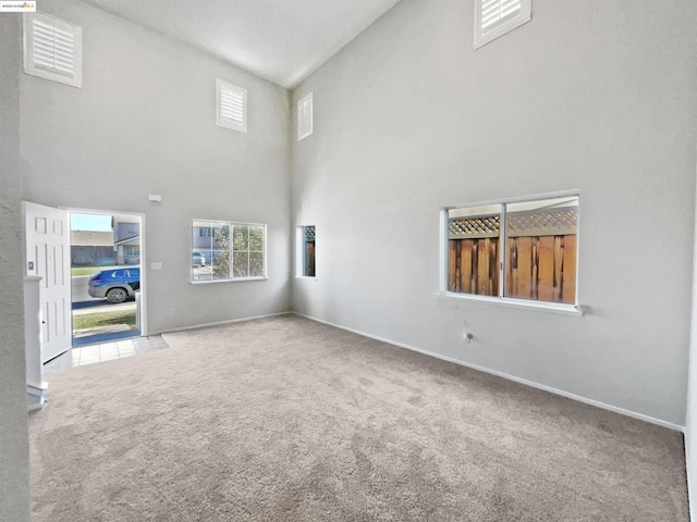 unfurnished living room featuring carpet and a towering ceiling