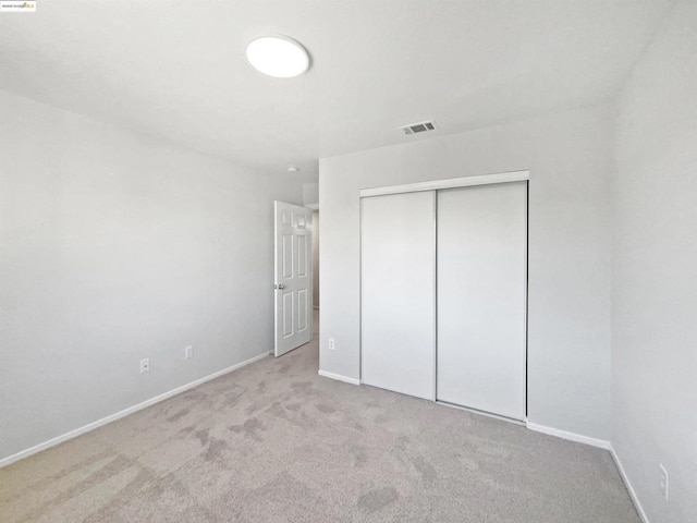 unfurnished bedroom with a closet and light colored carpet