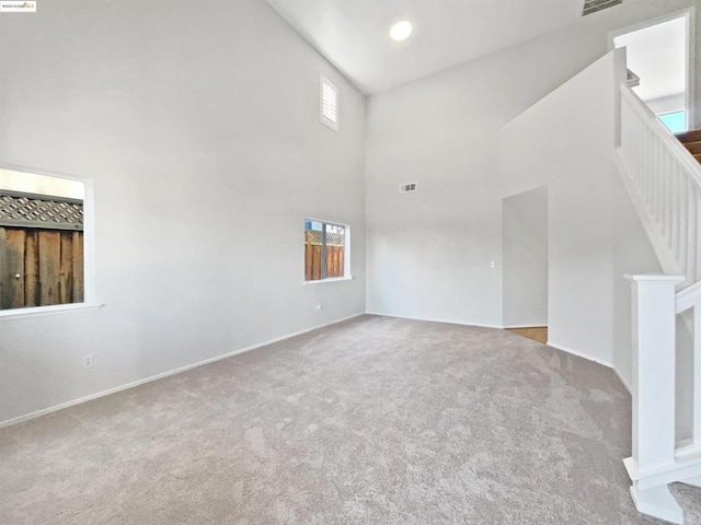 unfurnished living room with light carpet and a high ceiling