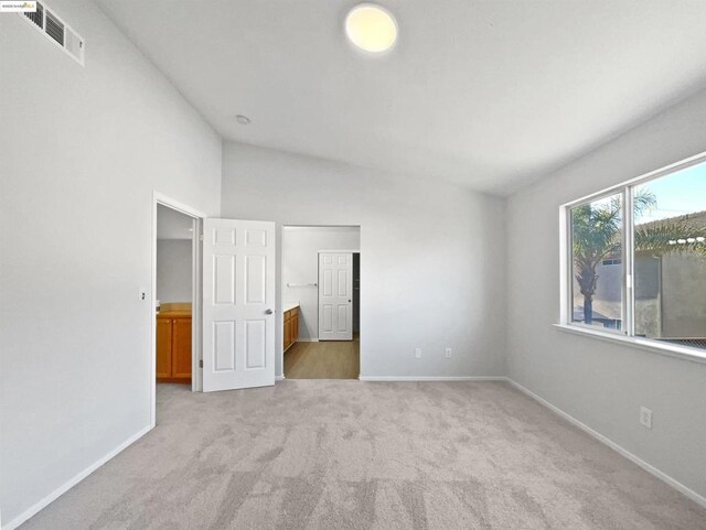 unfurnished bedroom featuring connected bathroom and light colored carpet