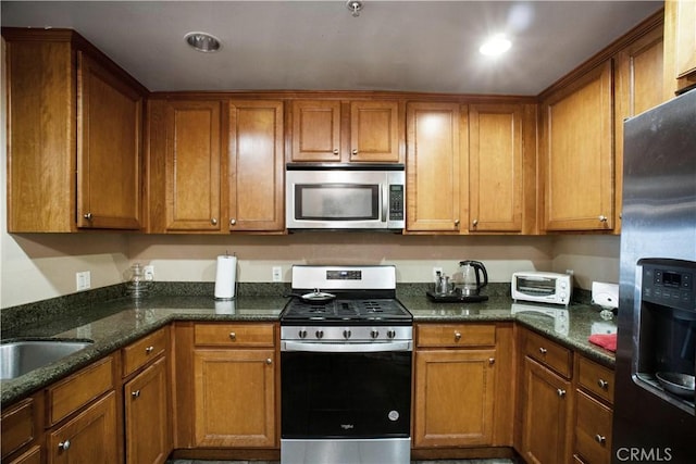 kitchen featuring sink, appliances with stainless steel finishes, and dark stone counters