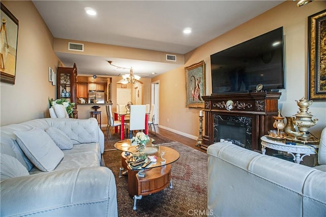 living room featuring hardwood / wood-style flooring, a high end fireplace, and an inviting chandelier