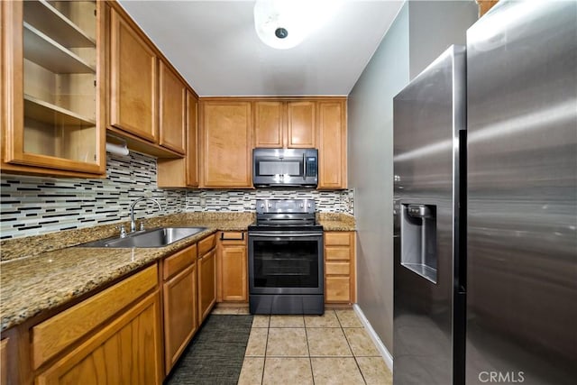 kitchen with appliances with stainless steel finishes, sink, backsplash, light stone counters, and light tile patterned floors