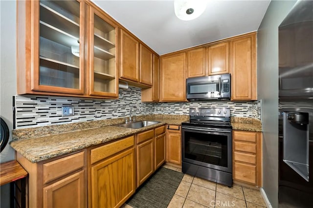 kitchen with light tile patterned floors, sink, stone countertops, and stainless steel appliances