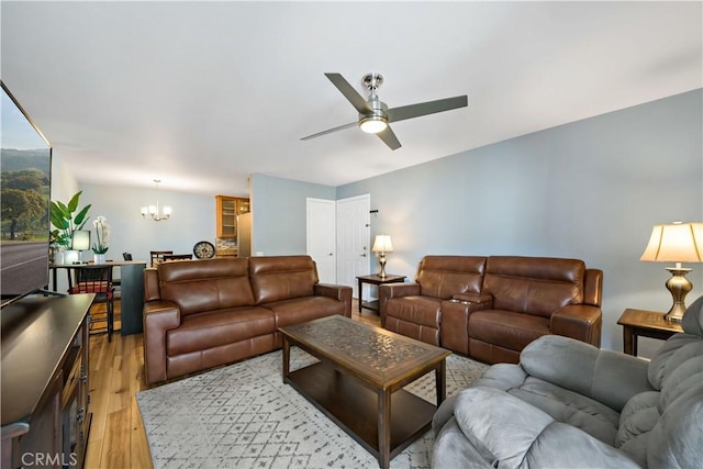 living room with ceiling fan with notable chandelier and light hardwood / wood-style flooring