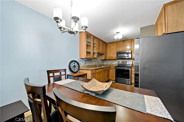 kitchen featuring pendant lighting, stainless steel appliances, tasteful backsplash, sink, and a notable chandelier