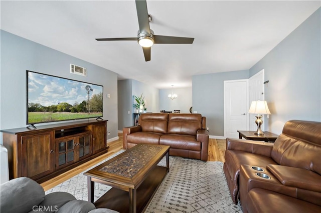 living room featuring light wood-type flooring and ceiling fan with notable chandelier