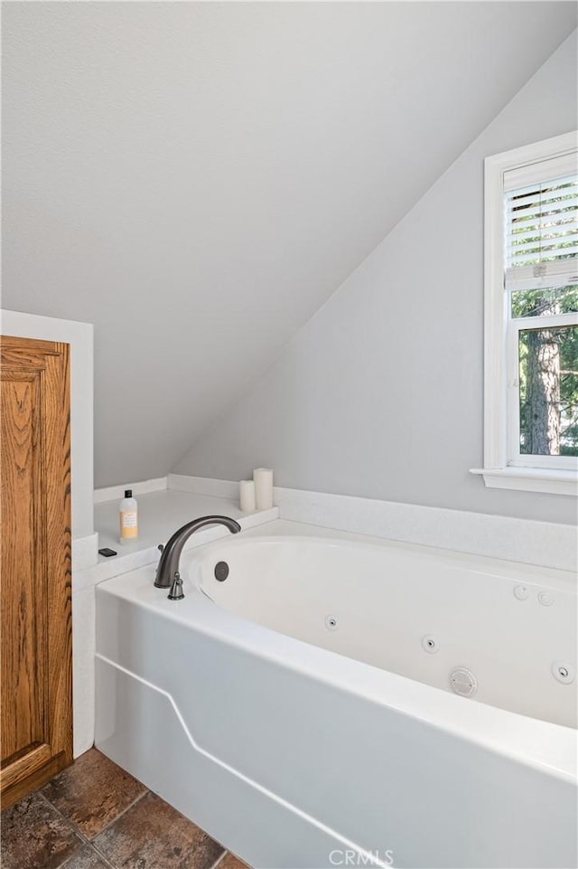 bathroom with lofted ceiling and a bathing tub